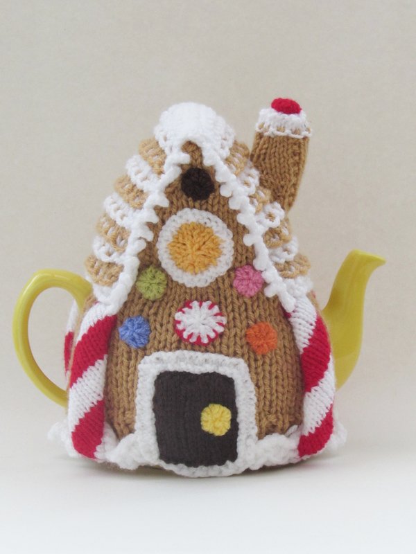 Knitted gingerbread house tea cozy with candy decorations on a yellow teapot