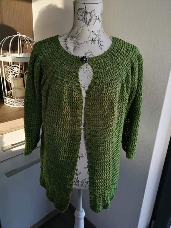 Grüne gehäkelte Damenjacke mit Rundhalsausschnitt und einem Knopf auf einer Schneiderpuppe