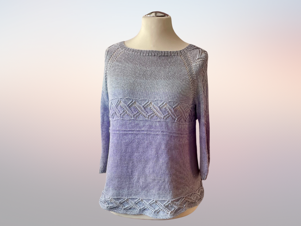 Gestrickter Damenpullover auf Schneiderpuppe mit Farbverlauf von Hellgrau zu Lila und Lochmustern am Brustbereich und Saum.