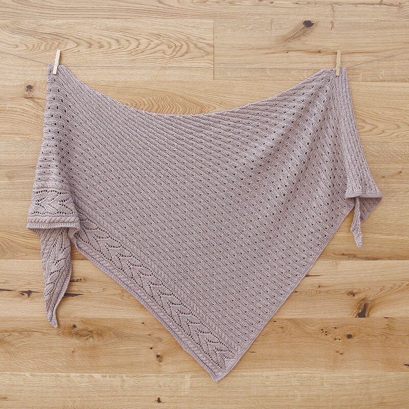 Gestricktes mauvefarbenes Dreieckstuch mit diagonalem Lochmuster und Blattkante an Holzwand
