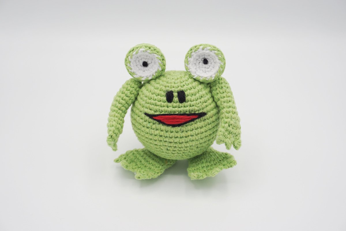 Gehäkelter hellgrüner Amigurumi-Frosch mit weißen Augen und rotem Mund