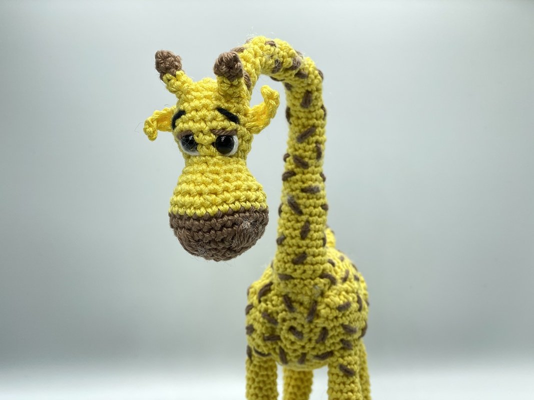 Gelbes gehäkeltes Giraffen-Amigurumi mit langem Hals und braunen Flecken