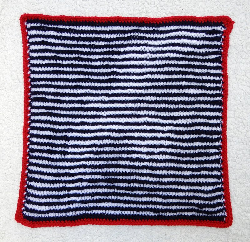 Gestricktes Quadrat mit blau-weißen Streifen und rotem Rand