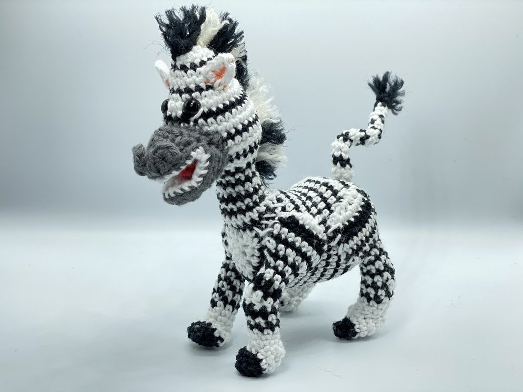 Vollansicht eines gehäkelten Amigurumi‑Zebras mit schwarz‑weißem Streifenmuster, stehend