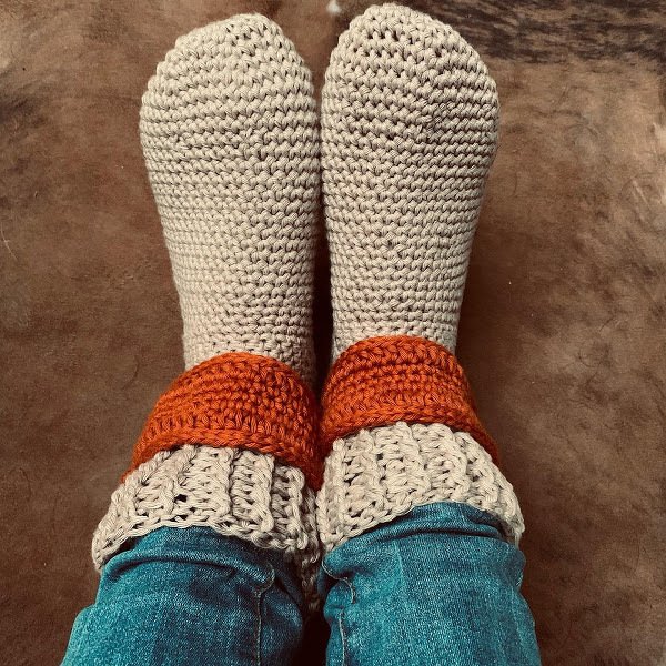 Beige gehäkelte Hausschuhe mit orangefarbenem Umschlag, getragen