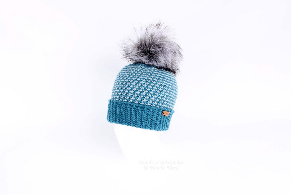 Teal and light grey crochet beanie with a grey faux fur pom pom.