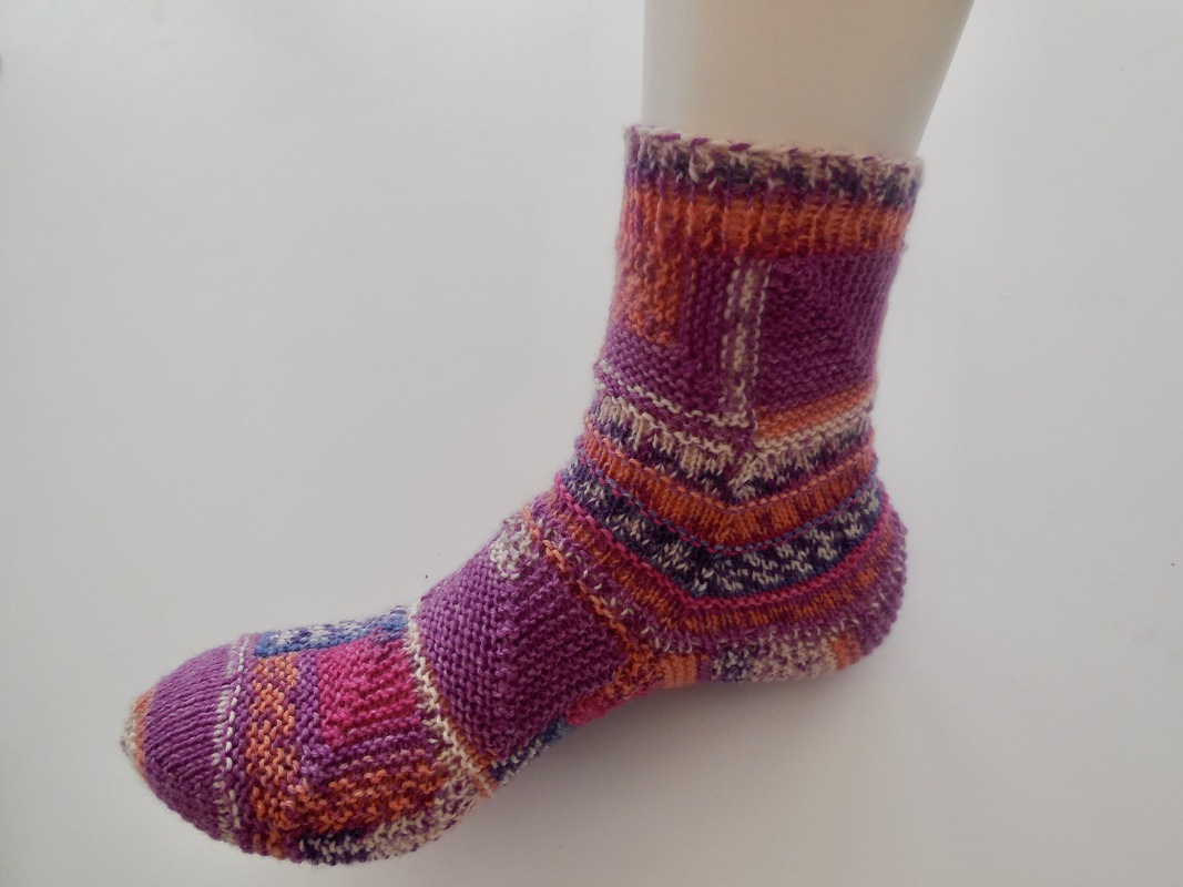 Lila-orange gestrickte Damensocke auf Schaufensterfuß, mehrfarbiges Garn