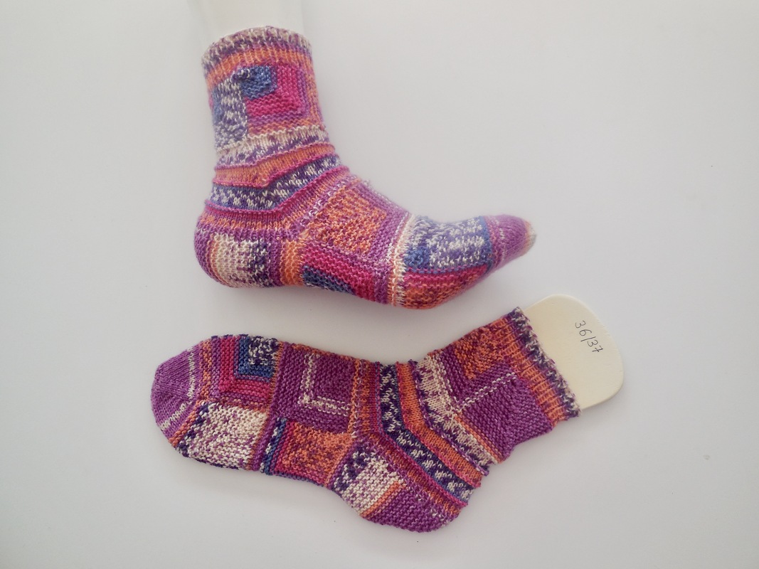 Paar handgestrickter bunter Damensocken in Patchmuster, eine auf Leiste mit Größe 36/37