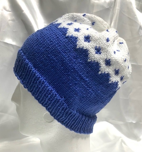 Blau-weiße gestrickte Mütze mit Zacken- und Punktmuster auf Schaufensterkopf