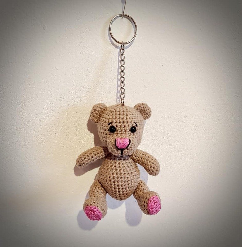 Hellbrauner gehäkelter Amigurumi-Teddybär als Schlüsselanhänger mit Metallkette, rosa Nase und rosa Pfoten an einem silbernen Schlüsselring