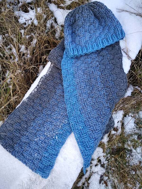 Gehäkelte Mütze und passender Schal in Blau‑Grau mit Strukturmuster auf Schnee
