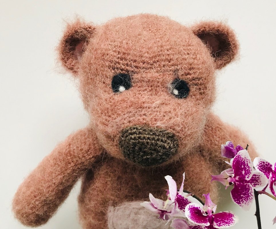 Nahaufnahme eines gehäkelten Amigurumi Teddybären, Fokus auf Nase, Augen und die flauschige Maschenstruktur