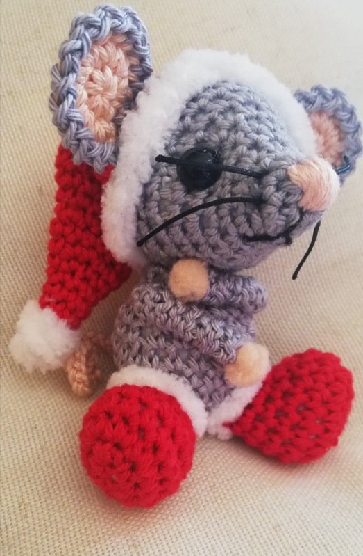 Gehäkelte graue Amigurumi‑Maus mit roter Weihnachtsmütze, roten Schuhen und schwarzen Knopfaugen