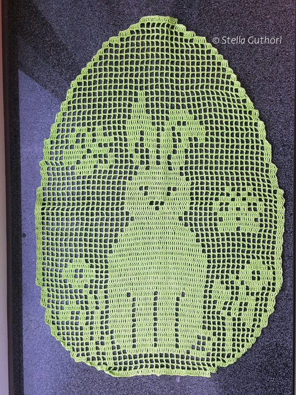 Lime-green egg-shaped filet crochet doily with rabbit and flower motifs