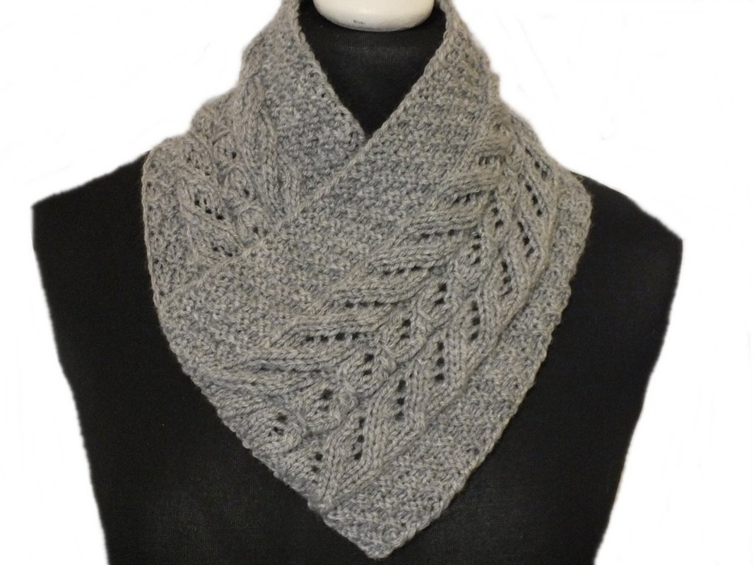 Gestrickter grauer Kragenschal mit Zopf- und Lochmuster auf schwarzer Schaufenpuppe