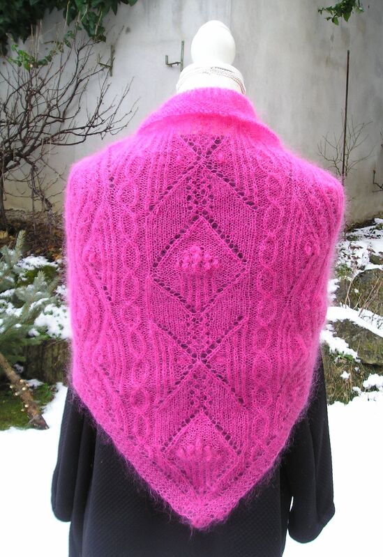 Fuchsiafarbenes gestricktes Dreieckstuch mit Ajour- und Zopfmustern, Rückansicht auf Schaufensterpuppe vor winterlicher Kulisse