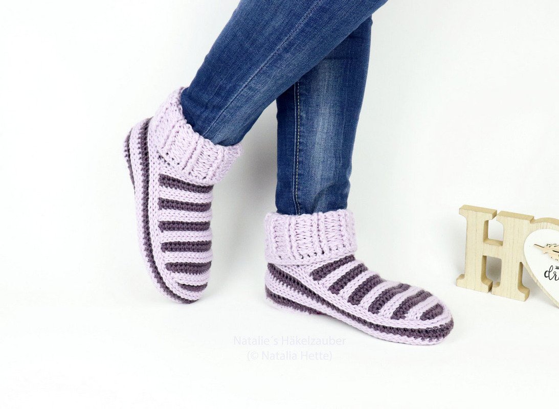 Zweifarbige Häkelsocken in Flieder und Dunkelgrau mit breitem Rippenbündchen und gestreiftem Fuß, seitliche Ansicht.