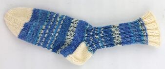 Handgestrickte Socke in Blau- und Cremetönen, liegend auf hellem Hintergrund