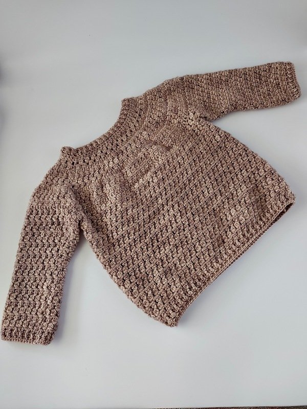 Gehäkelter Kinderpullover beige mit Strukturmuster, flach liegend