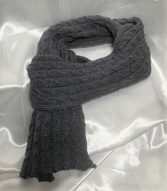 Dunkelgrauer gestrickter Schal mit Zopfmuster auf hellem Untergrund