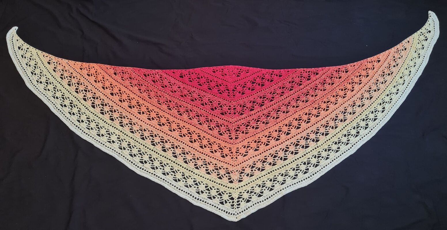 Gehäkeltes Dreieckstuch mit Farbverlauf (Rot→Orange→Gelb→Creme) und Spitzenmuster auf dunklem Hintergrund