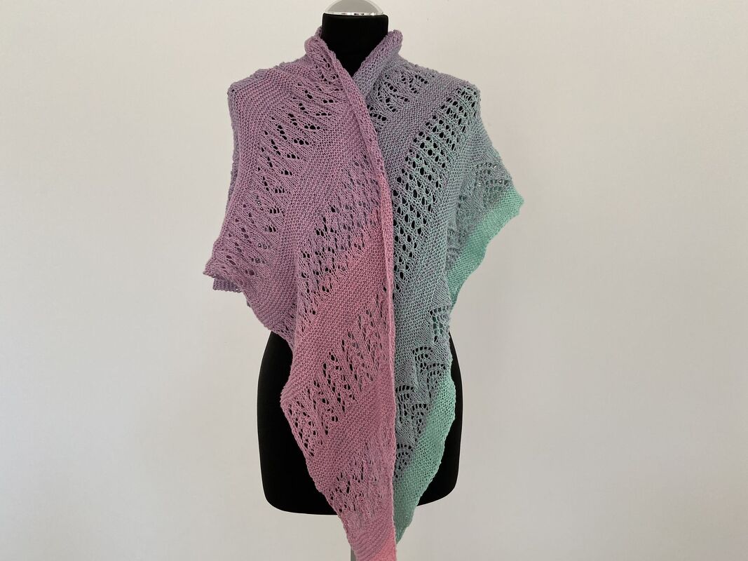 Gestricktes Dreieckstuch in Pastellverlauf (Rosa–Flieder–Mint) mit Ajour‑Lochmuster auf schwarzer Schneiderpuppe