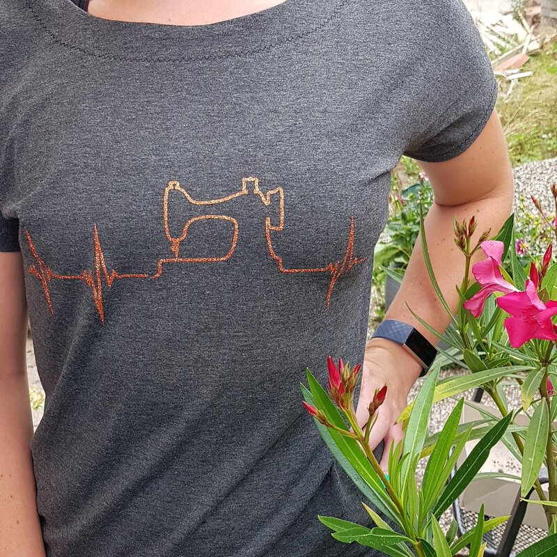 Graues T
-Shirt mit orangefarbenem Plot: Nähmaschinenumriss in Herzschlaglinie