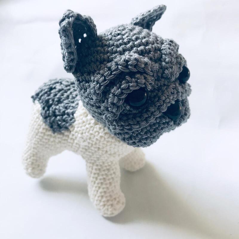 Gray and white crocheted amigurumi dog with large black eyes