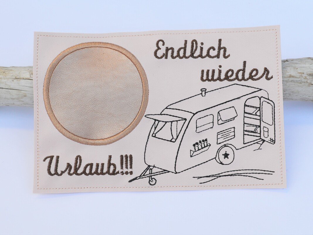 Beigefarbener bestickter Patch mit Wohnwagen-Umriss, dem Schriftzug 'Endlich wieder Urlaub!!!' und rundem Ledereinsatz