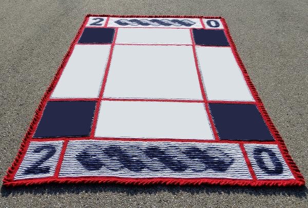 Rechteckige Strickdecke in Weiß, Dunkelblau und Rot mit Gitterfeldern, Zopfmuster an den kurzen Seiten, roten Fransen und eingestrickten Zahlen "20".