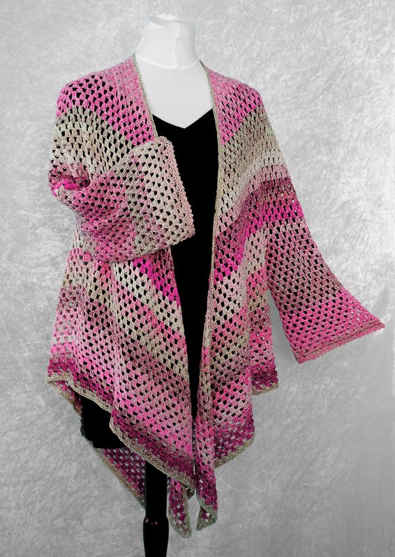 Open-front crocheted cardigan in pink and beige displayed on a mannequin over a black top.