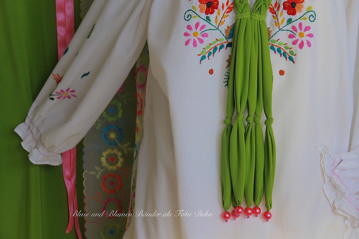 Weiße Bluse mit floraler Stickerei, gerüschten Ärmelbündchen und geknotetem grünem Zierband mit Perlen