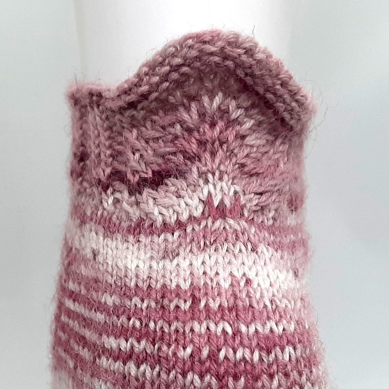 Nahaufnahme eines rosa-weiß gestreiften gestrickten Sockenbundes mit dekorativer Kante.