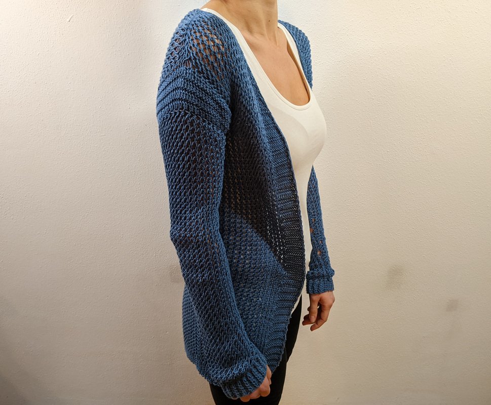 Dunkelblaue, offene Strickjacke mit Lochmuster über weißem Top.