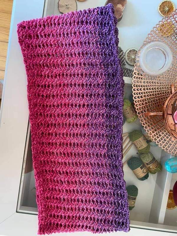 Gehäkelter Loop mit Pink‑Violettem Farbverlauf auf Tisch neben Wollknäueln