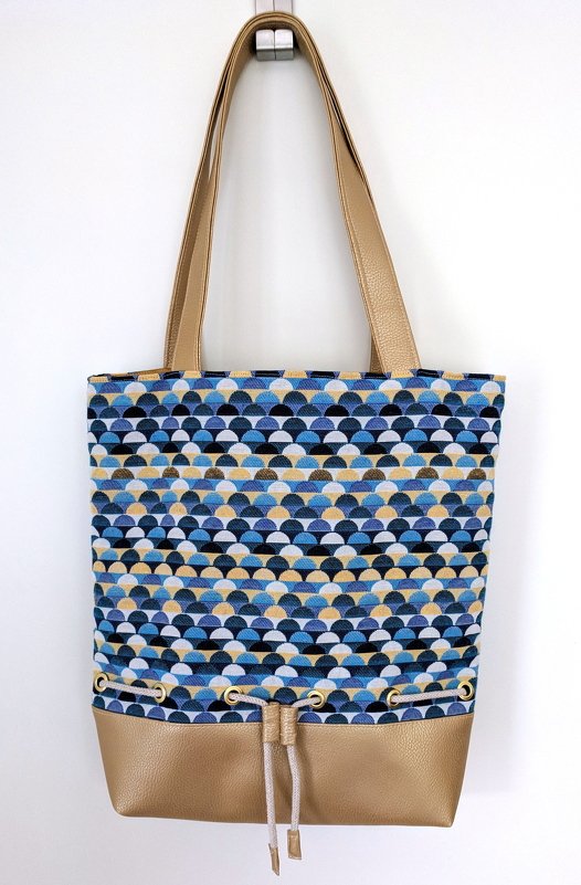 Stofftasche mit blau-gelbem Schuppenmuster, goldfarbenem Kunstlederboden und Kordelzug
