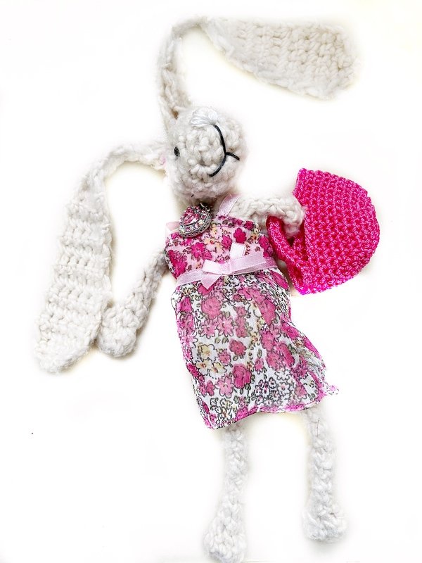 Weißer gehäkelter Amigurumi-Hase mit langen Ohren, floralem Kleid und pinkem Häkelaccessoire