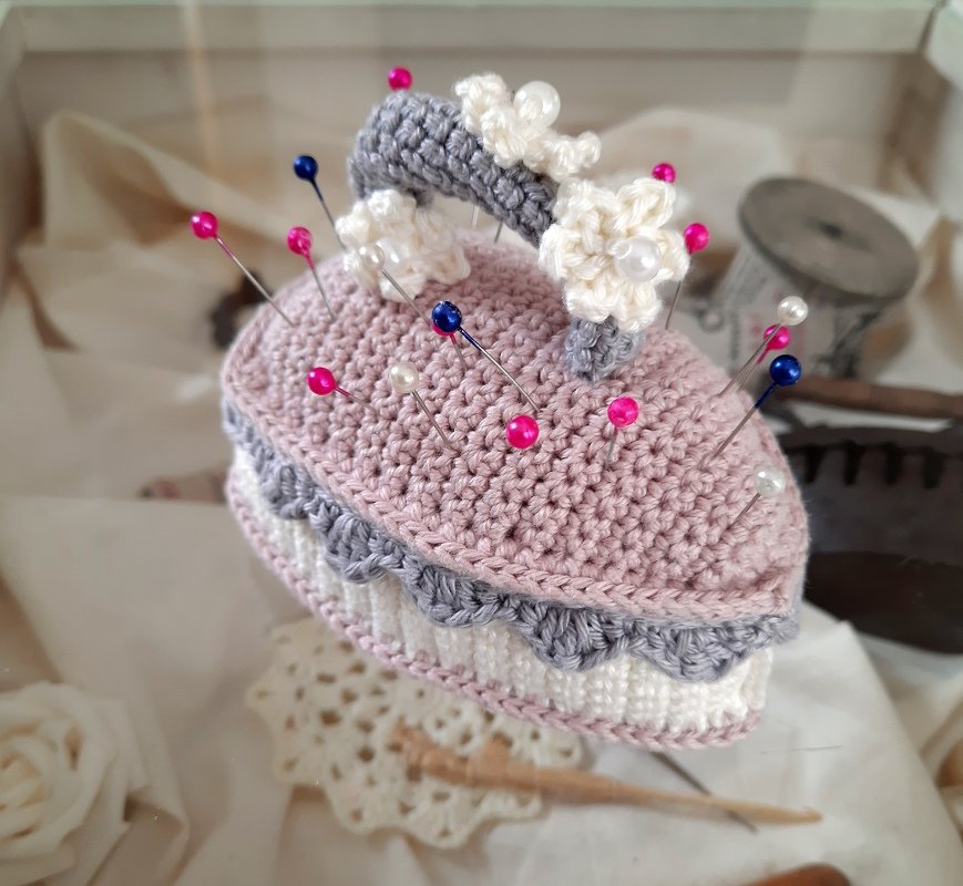 Gehäkeltes Nadelkissen in Rosa, Grau und Weiß mit Blüten und bunten Stecknadeln