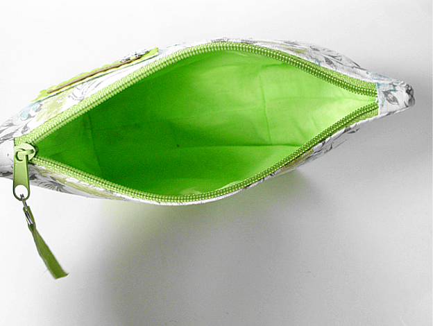 Weit geöffnete Kosmetiktasche mit floralem Außenstoff und leuchtgrünem Innenfutter