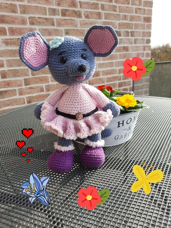 Gehäkelte Amigurumi-Maus mit rosa Kleid und lila Stiefeln, neben Blumentopf stehend