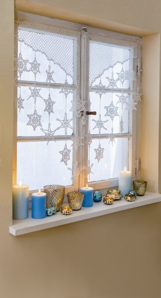 DIY-Fensterdeko mit gehäkelten Sternen an Schnur und Kerzen auf dem Fensterbrett