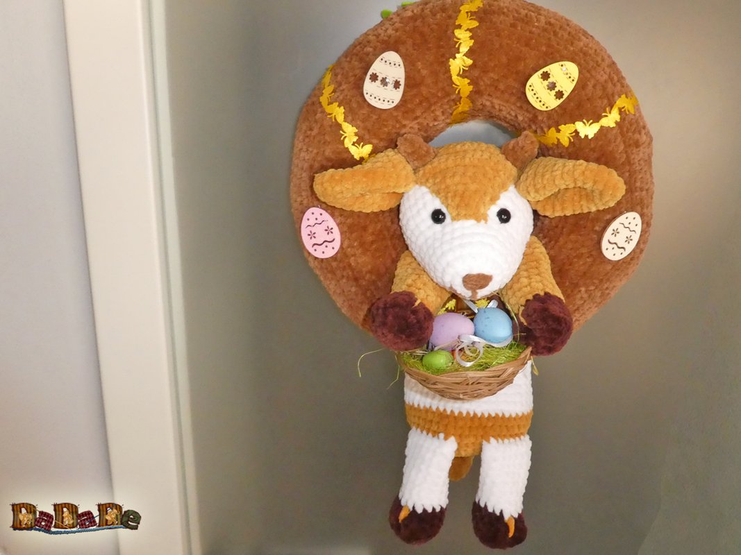 Detailansicht eines gehäkelten braunen Türkranzes mit Rehkitz und Korb mit pastellfarbenen Ostereiern.