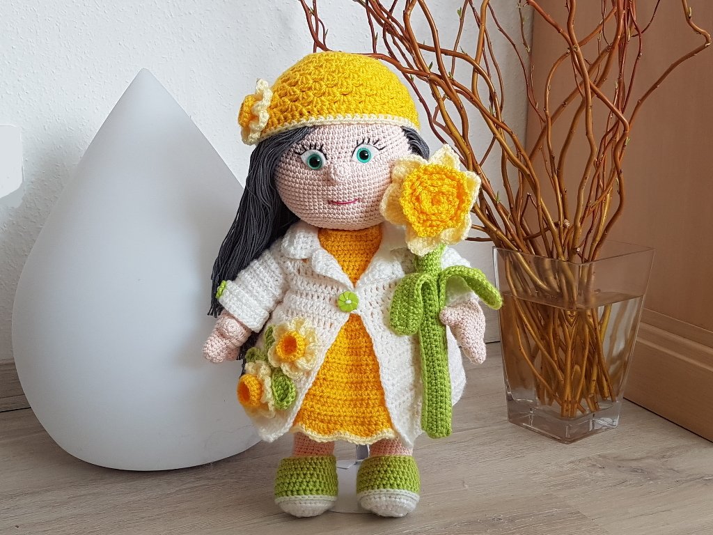 Gehäkelte Puppe mit gelbem Kleid, weißem Mantel und gehäkelter Narzisse