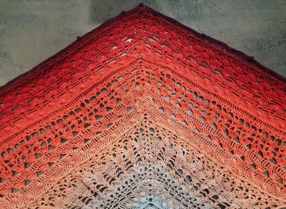 Gehäkeltes Dreieckstuch in Ombre-Verlauf von Creme, Pfirsich bis Rot mit detailliertem Lochmuster