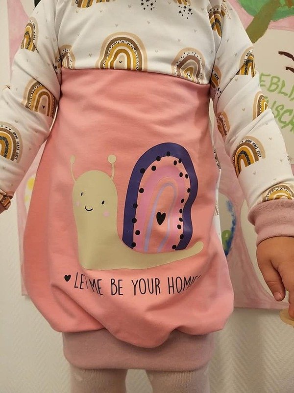 Kleinkind in rosa Kleid mit Schnecken-Plot und Regenbogenärmeln