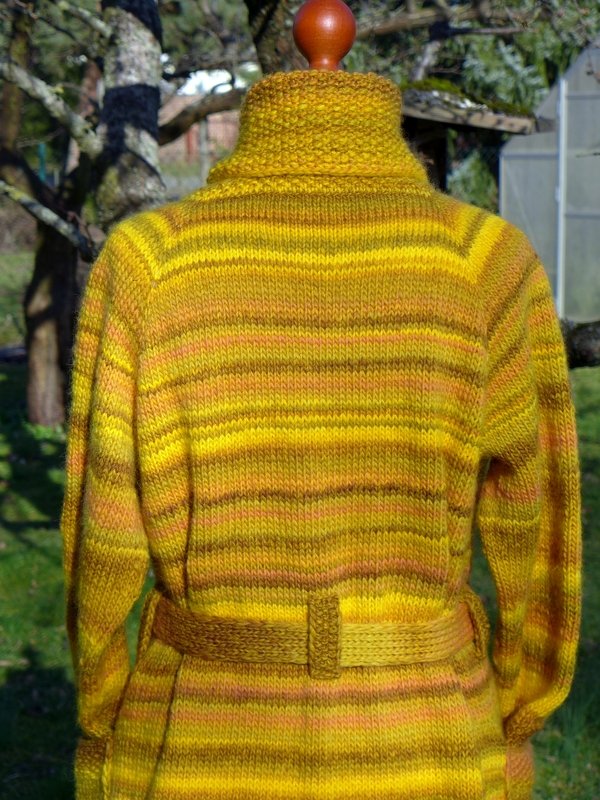 Rückansicht gestrickte Damenjacke in Gelb- und Brauntönen mit Streifen und Taillengürtel auf Puppe im Freien.