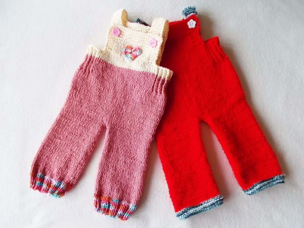 Zwei gestrickte Kinderlatzhosen, links rosa mit cremefarbener Brust und Herz, rechts rot mit kontrastfarbigen Bündchen