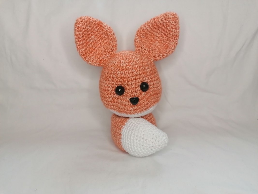 Orange-weißes gehäkeltes Fuchs-Amigurumi mit großen Ohren und schwarzen Augen