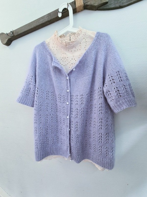 Lavendelfarbener gestrickter Kurzarm-Cardigan mit Lochmuster und perlmuttartigen Knöpfen auf Kleiderbügel