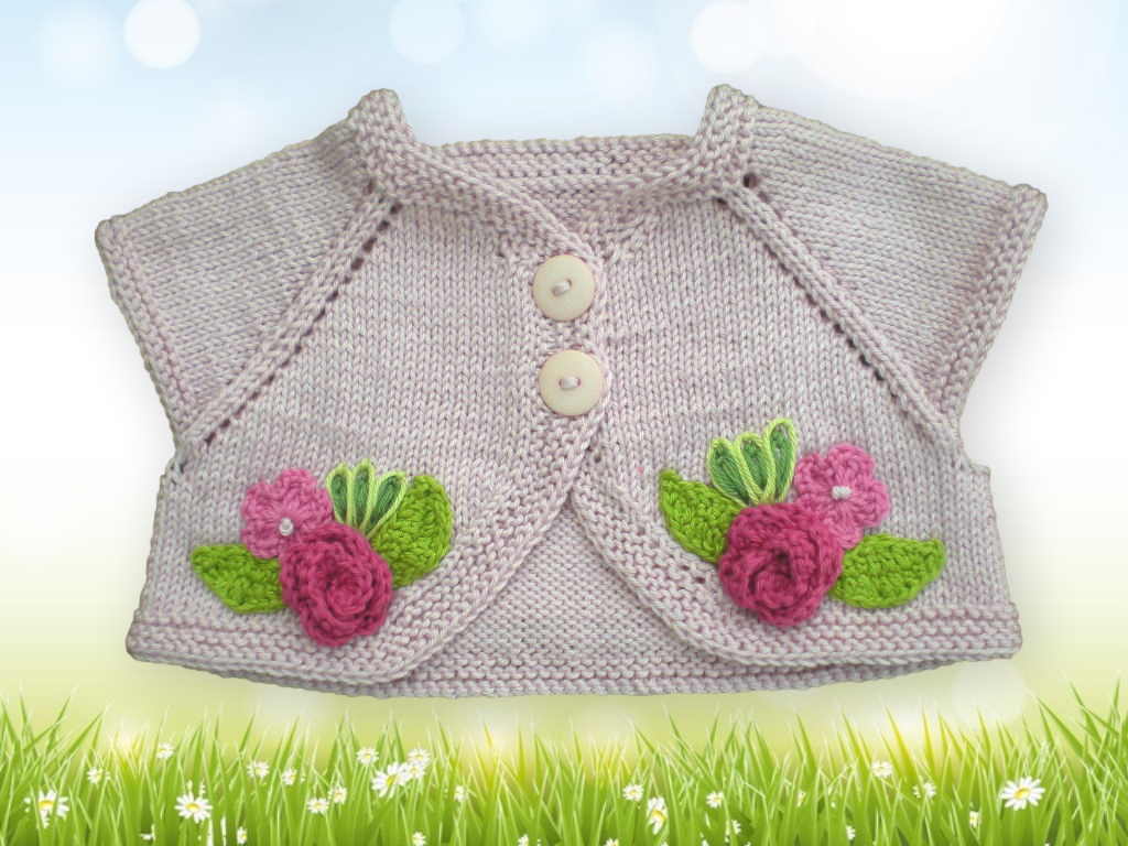 Hellrosa gestrickter Babybolero mit kurzen Ärmeln und Blumenapplikationen